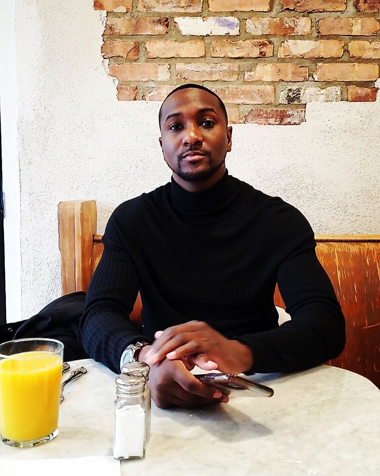James Houston seated in a black knit at a cafe table.